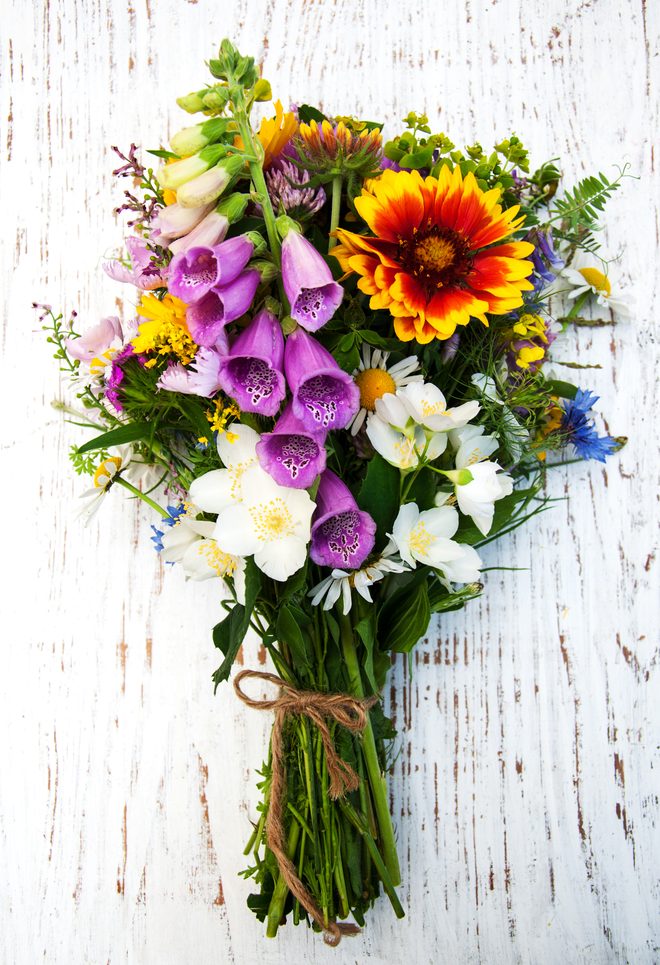 A rustic hand-tied bouquet of sunflowers and daisies
