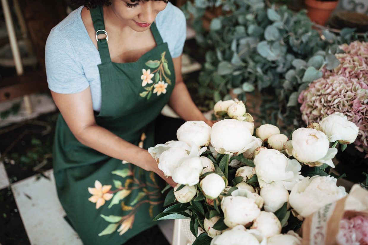 A florist arranging white peonies in a flower shop
